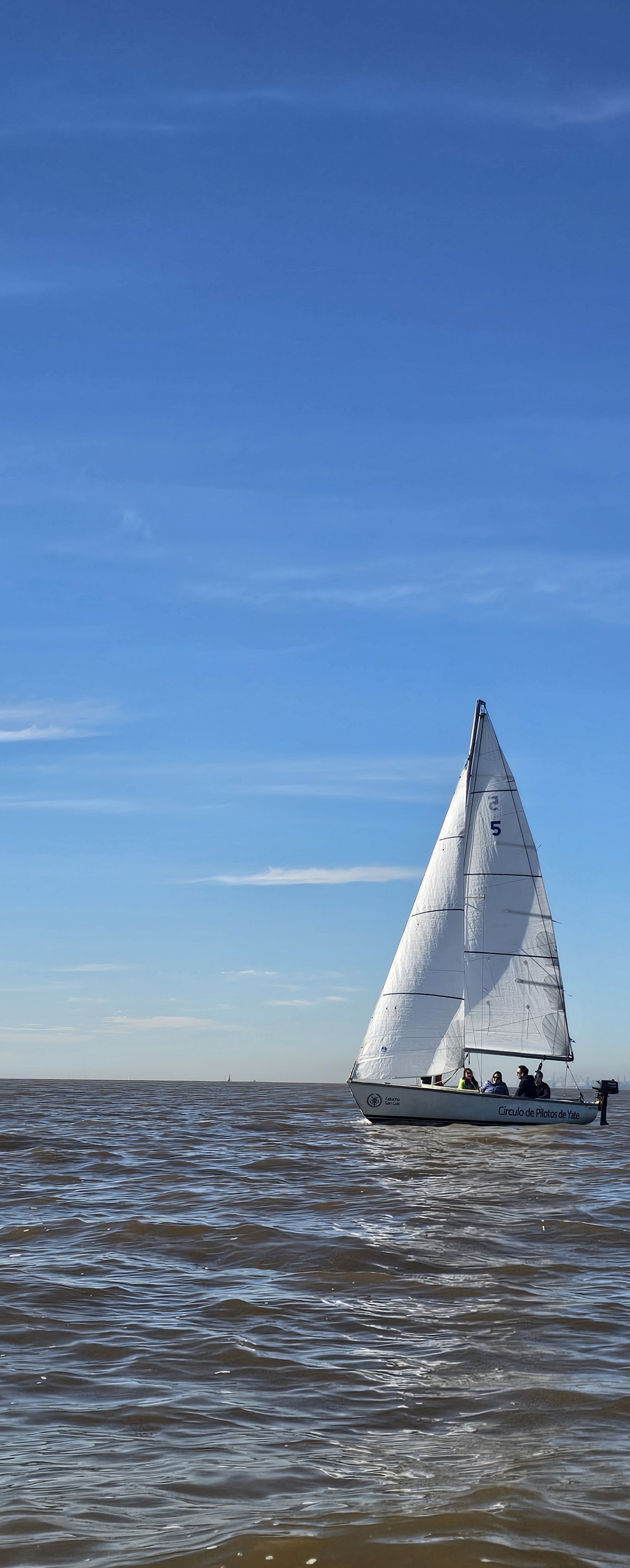 Velero completo navegando con tripulación en el Río de la Plata